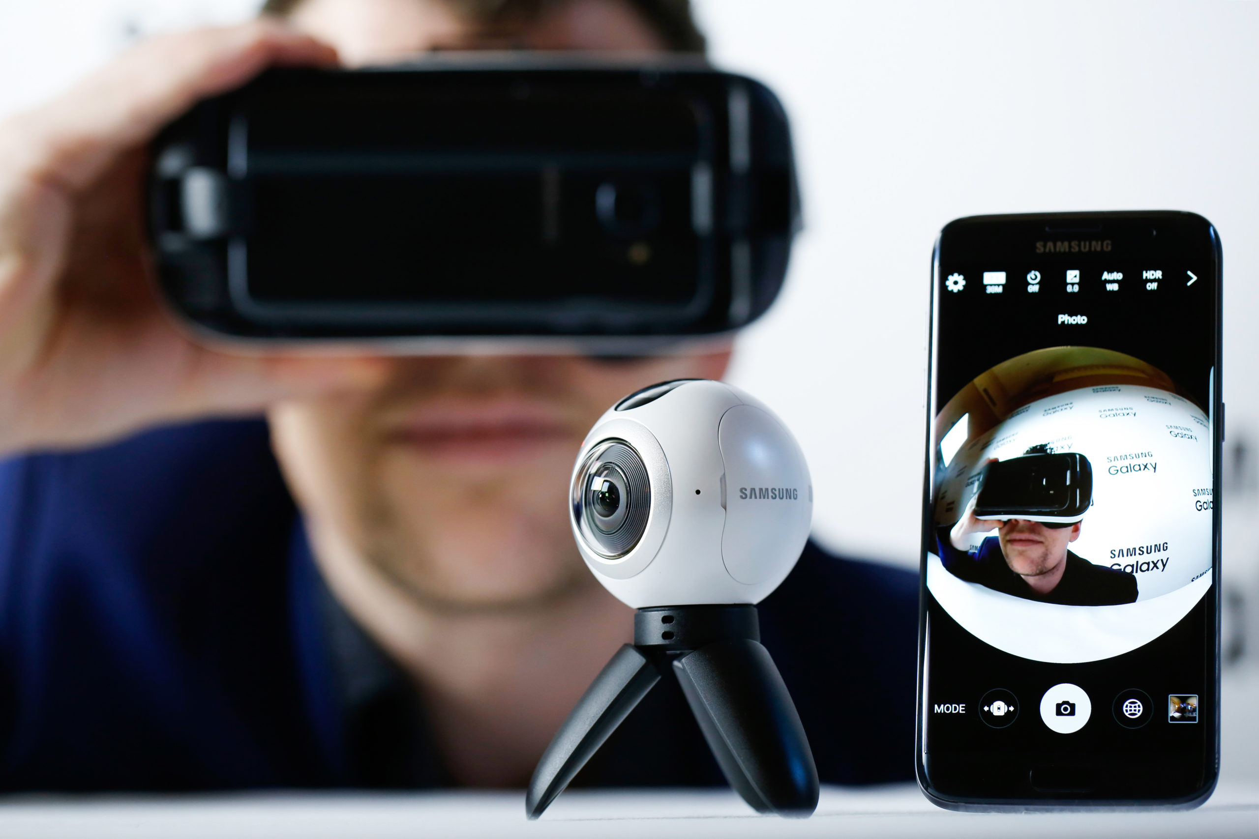 An employee demonstrates the previously released Samsung Electronics Co. Gear VR, left, in combination with the new Samsung Gear 360, video camera, centre, as it sends 360 degree footage to the Samsung Galaxy S7 edge with 3D thermo forming in this arranged photo in London, U.K., on Thursday, Feb. 18, 2016.  Samsung showed off new Galaxy S7 smartphones featuring upgraded components and the return of a popular feature missing from their predecessors, in the latest attempt to breathe life into its premium line and wrest ascendancy back from Apple Inc. Photographer: Luke MacGregor/Bloomberg